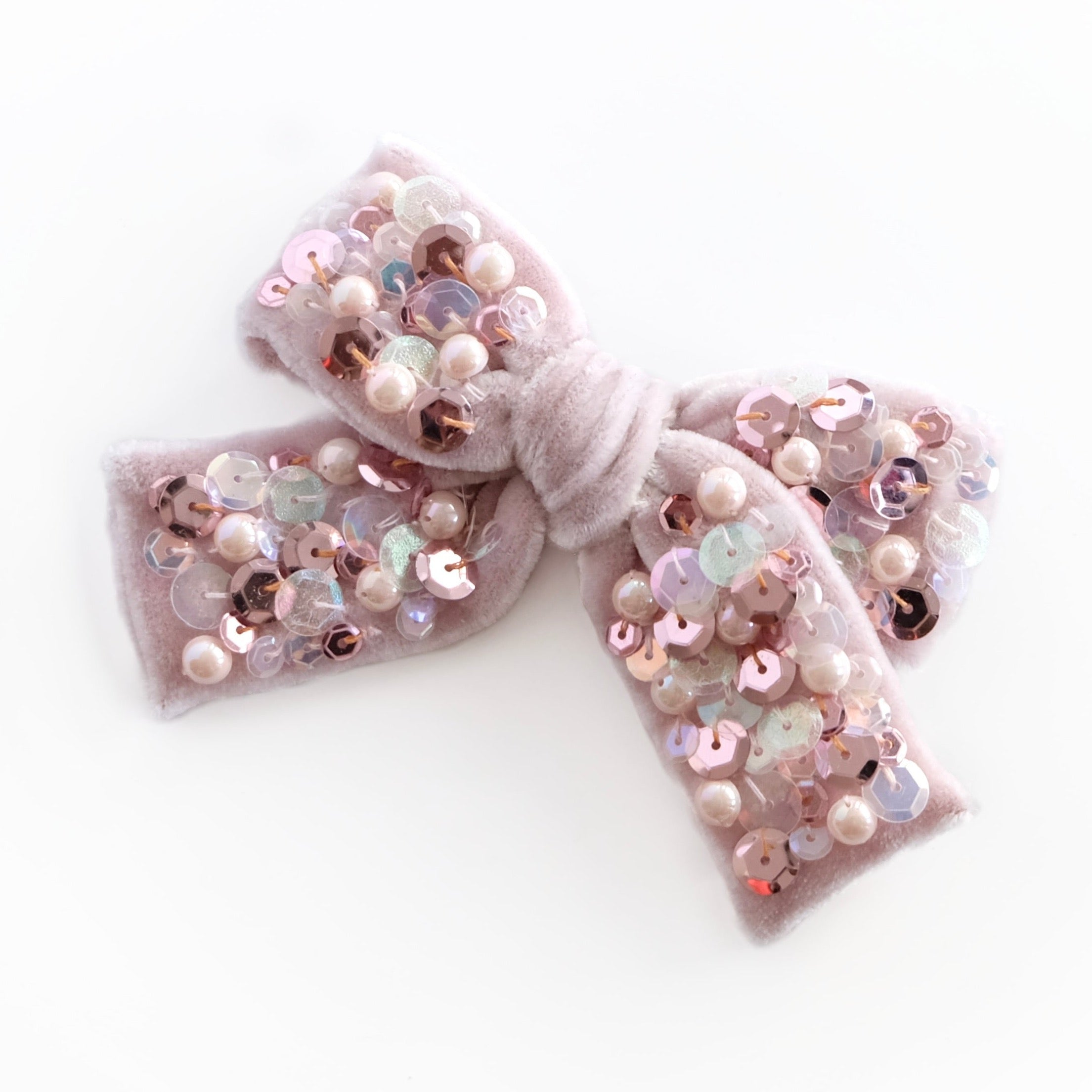 Sequin hair bow with pearls in pink tones.