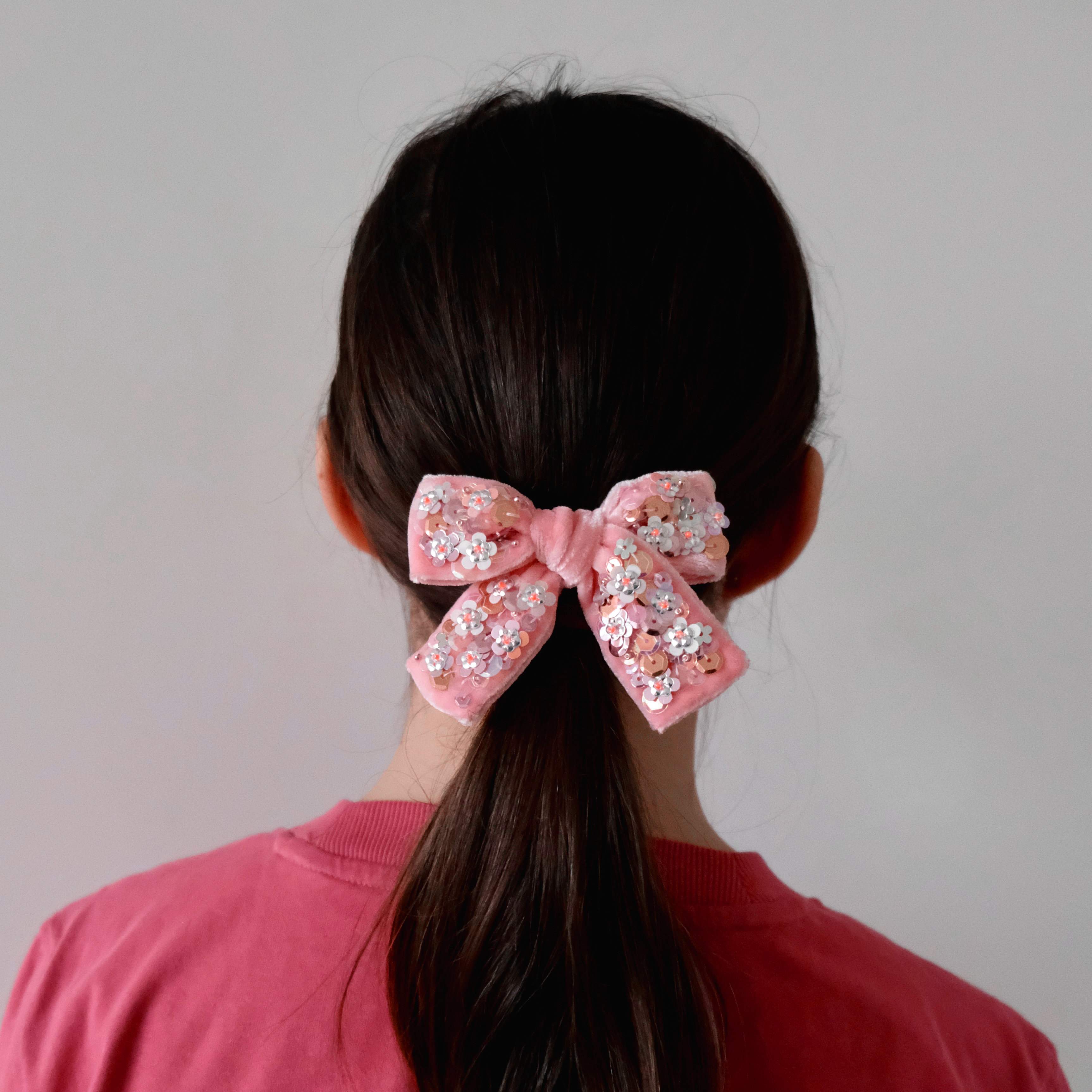 School girl with baby pink velvet hair bow embellished with sequins.