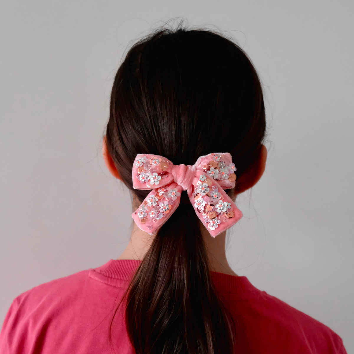 School girl with baby pink velvet hair bow embellished with sequins.