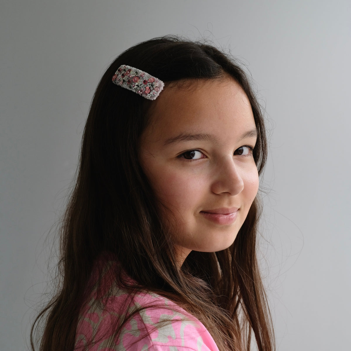 Girl wearing a doodle.lidoo rectangular snap hair clip with sparkly sequins. 
