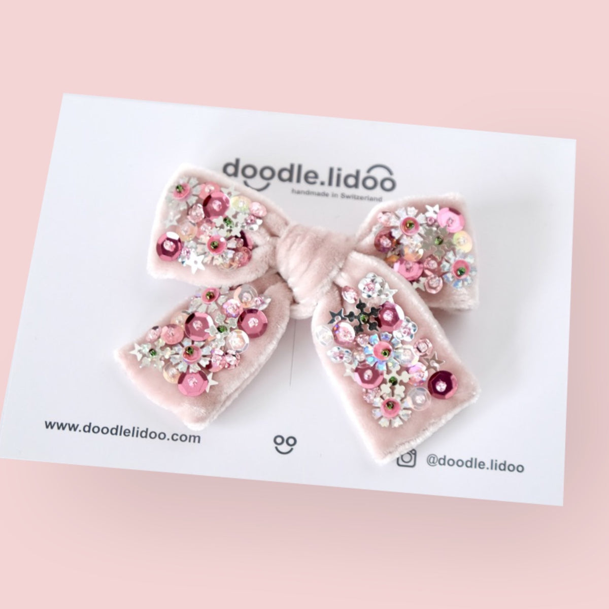 Hair bow made from pale pink velvet and embellished with silver and pink flower shaped sequins.