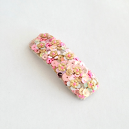 Large snap hair clip covered in velvet and embellished with sequins in gold and pink colors.