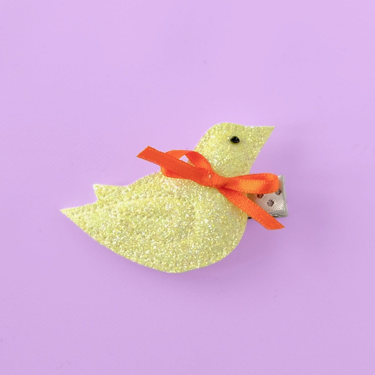 small bird hair clip in yellow on purple background